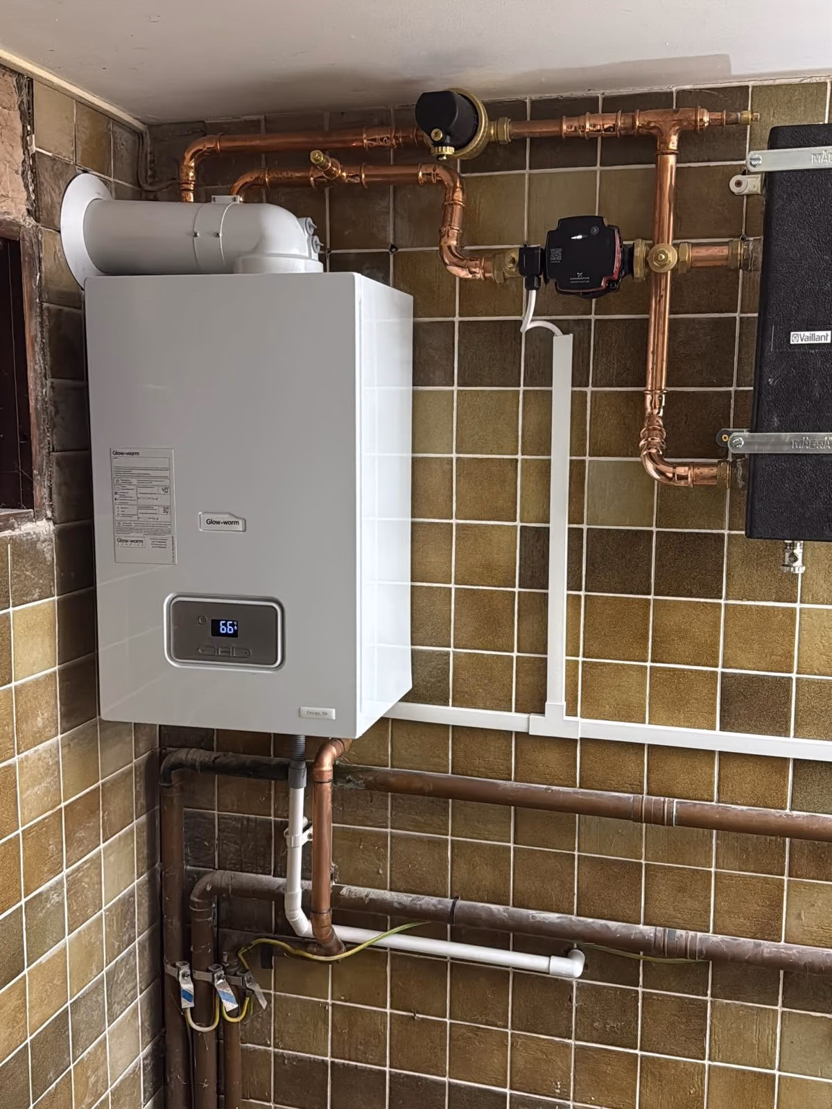 Newly installed wall-mounted combi boiler with neat copper pipework and a magnetic system filter