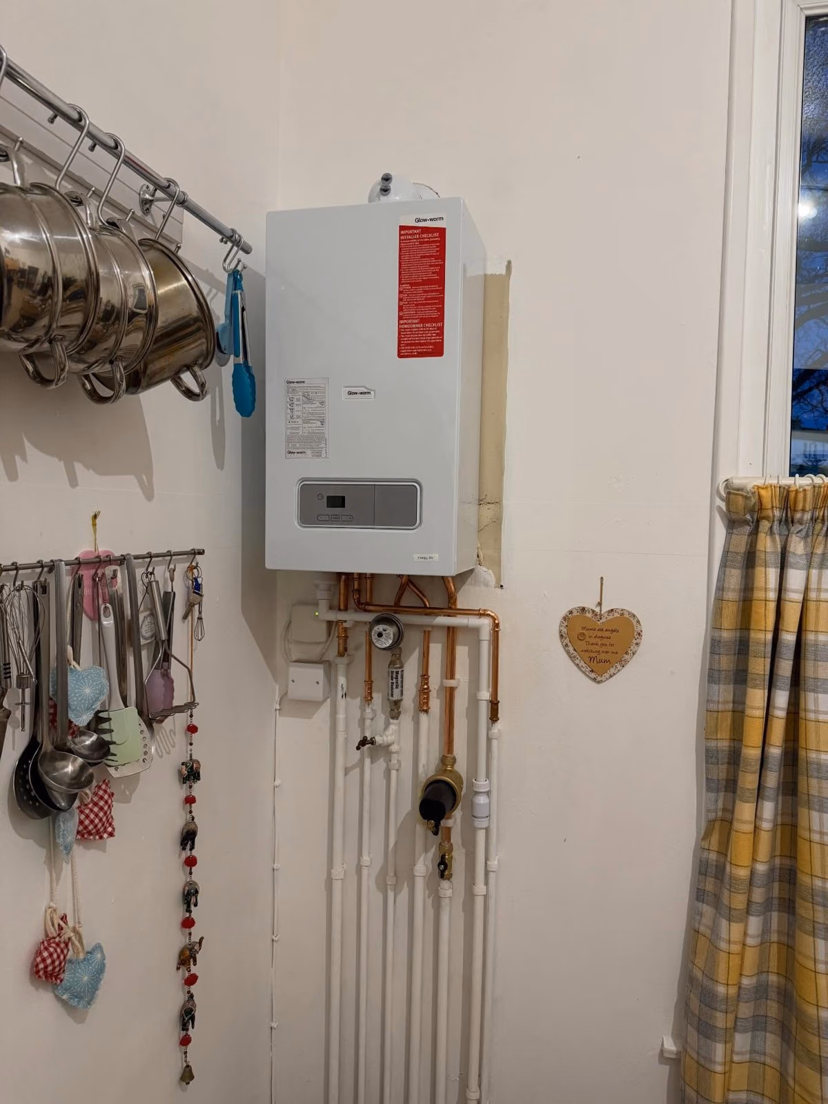 Neatly fitted white combi boiler on a kitchen wall with tidy pipework below